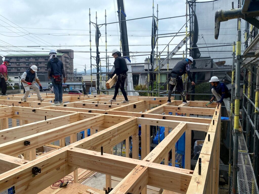 上棟現場で木造の梁を組み上げる大工たち