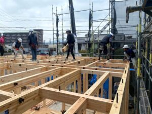 上棟現場で木造の梁を組み上げる大工たち